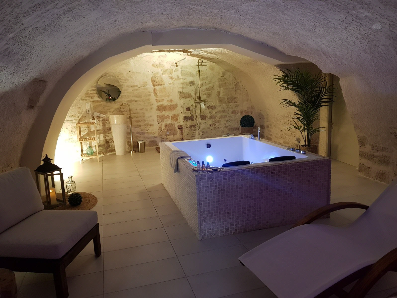 Suite spa avec jacuzzi sous voûte en pierre, éclairage tamisé